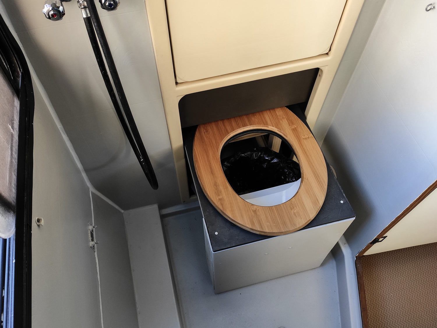 Compact campervan compost toilet with wooden seat.