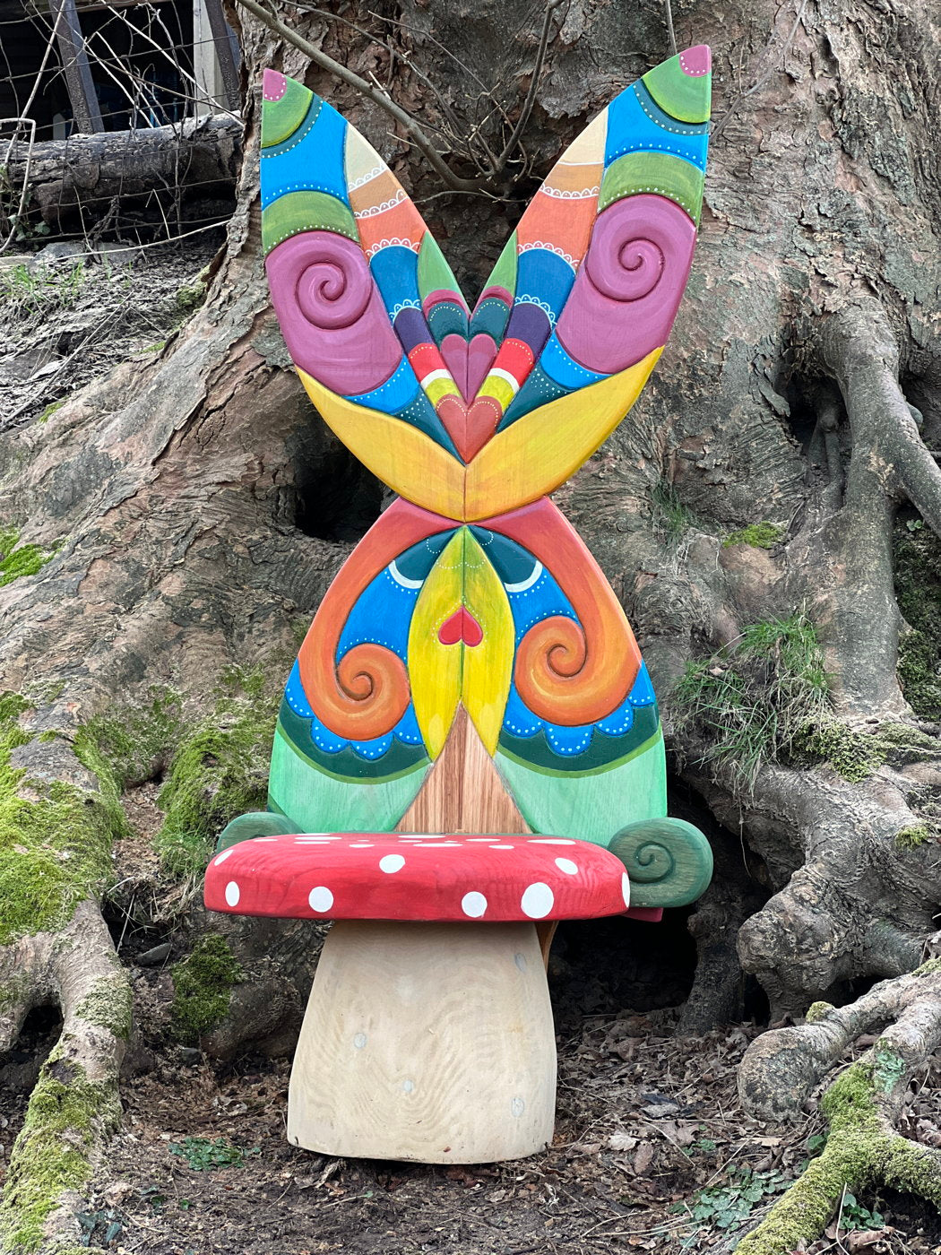 Colorful fairy chair with butterfly wings by tree roots