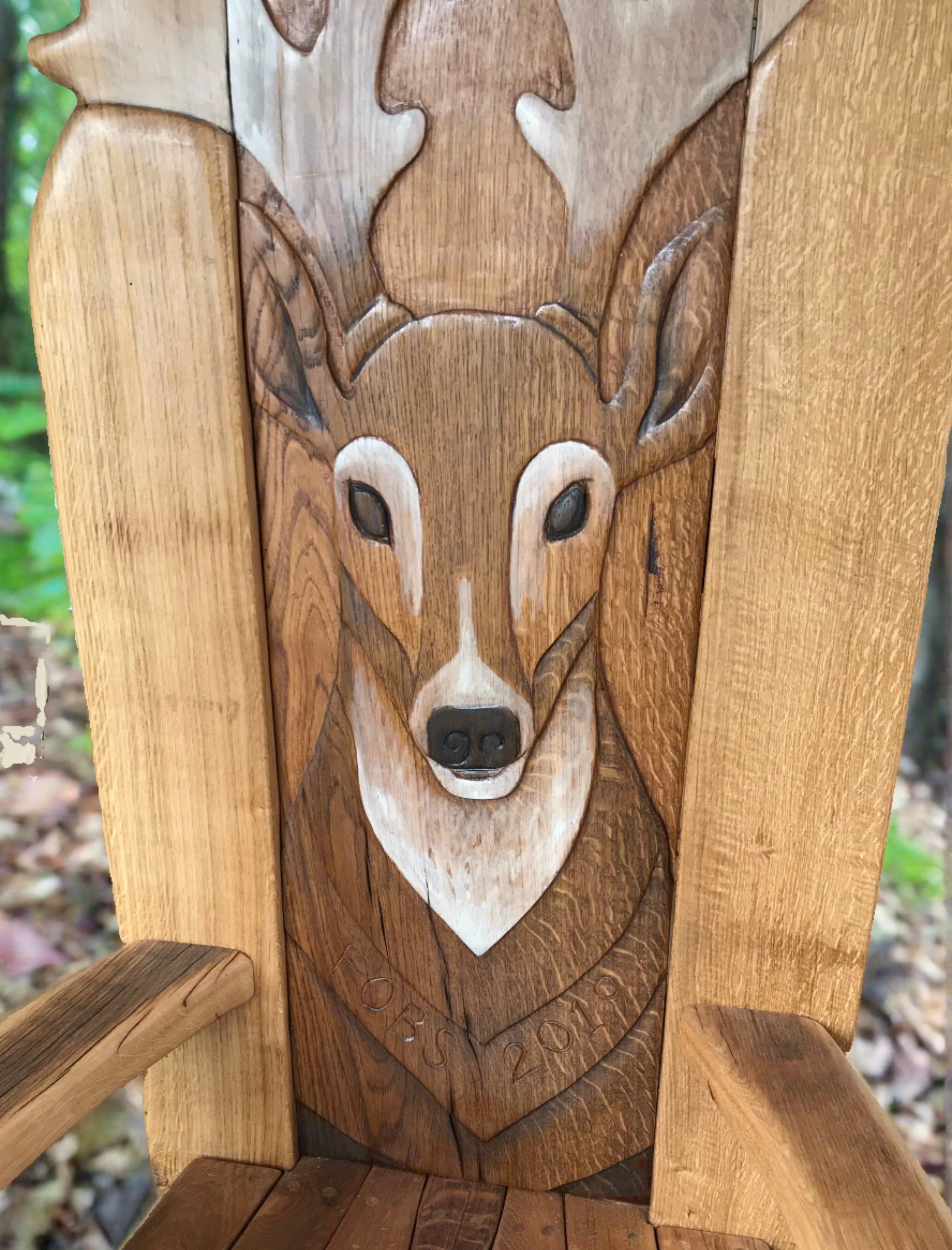 Close-up of deer carving on wooden chair.