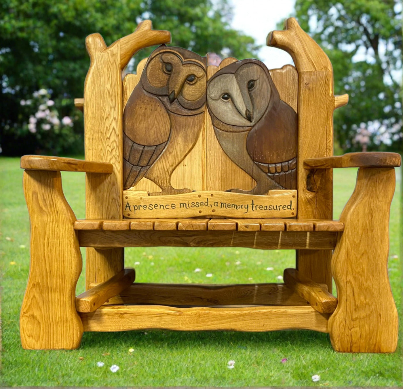 Oak memorial garden bench with carved owls and inscription.