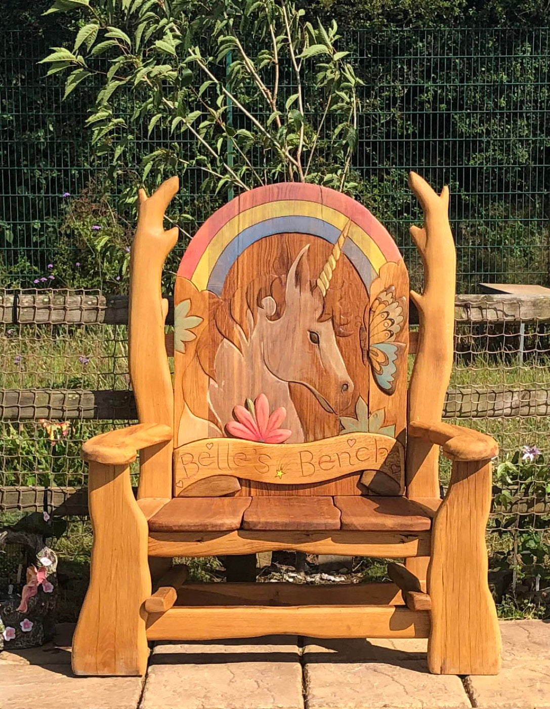 Unicorn-themed wooden bench with colorful carvings.