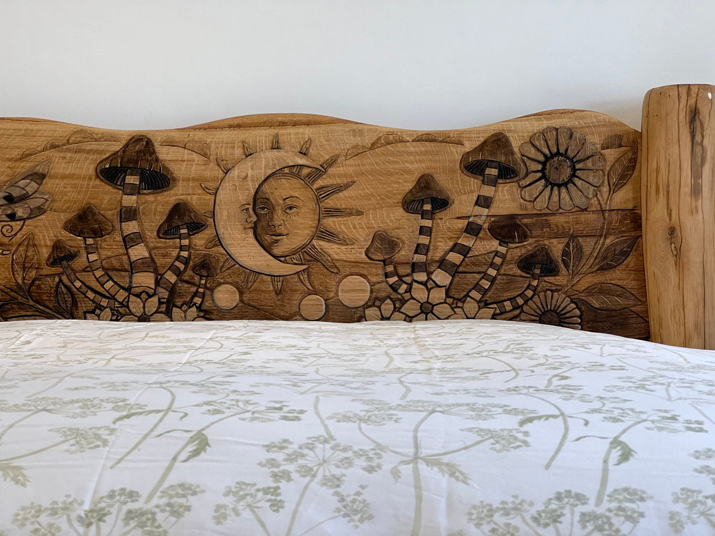 Headboard carvings of mushrooms and sun on oak bed