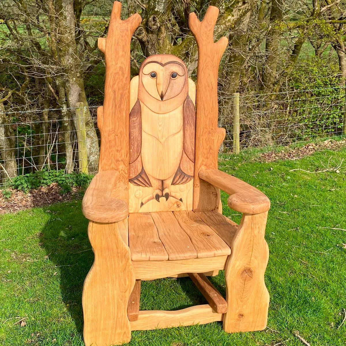 Carved owl reading chair on green grass