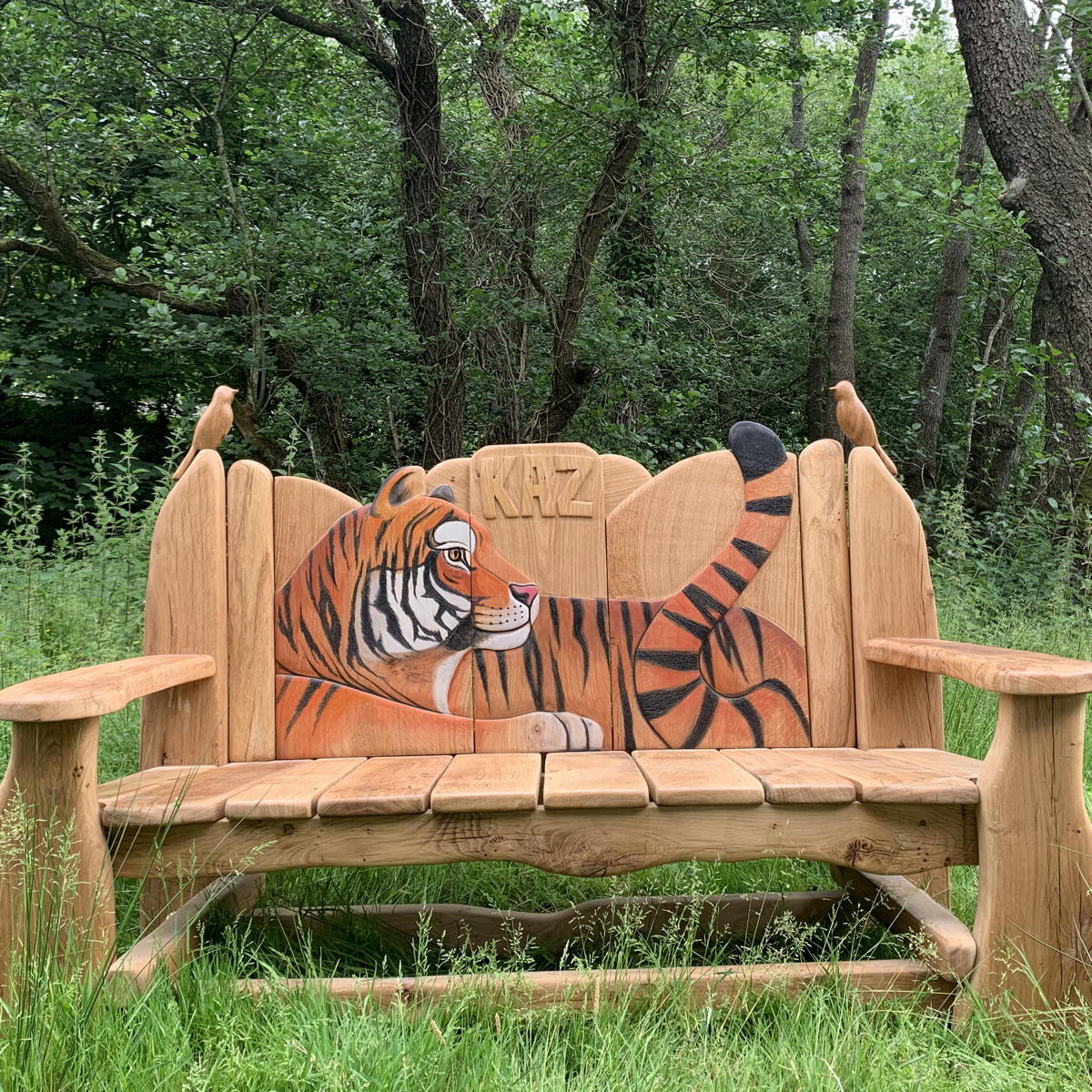 Wooden bench with carved tiger design in a forest setting