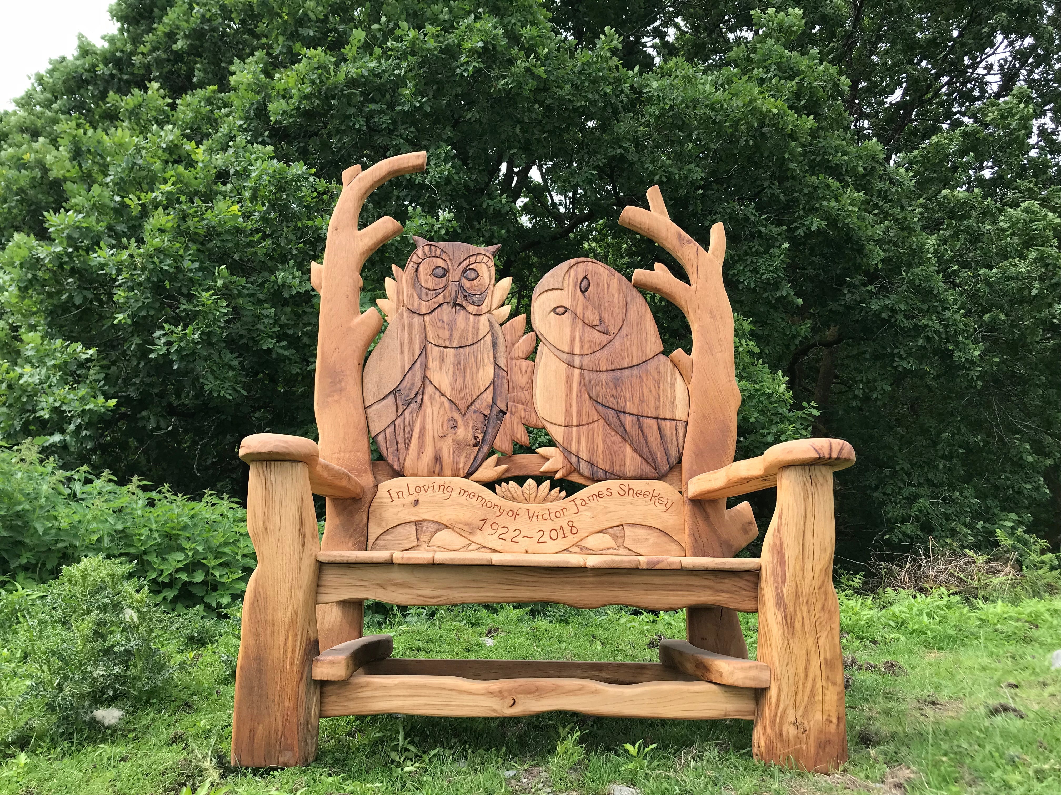 Owl-themed wooden memorial bench in nature