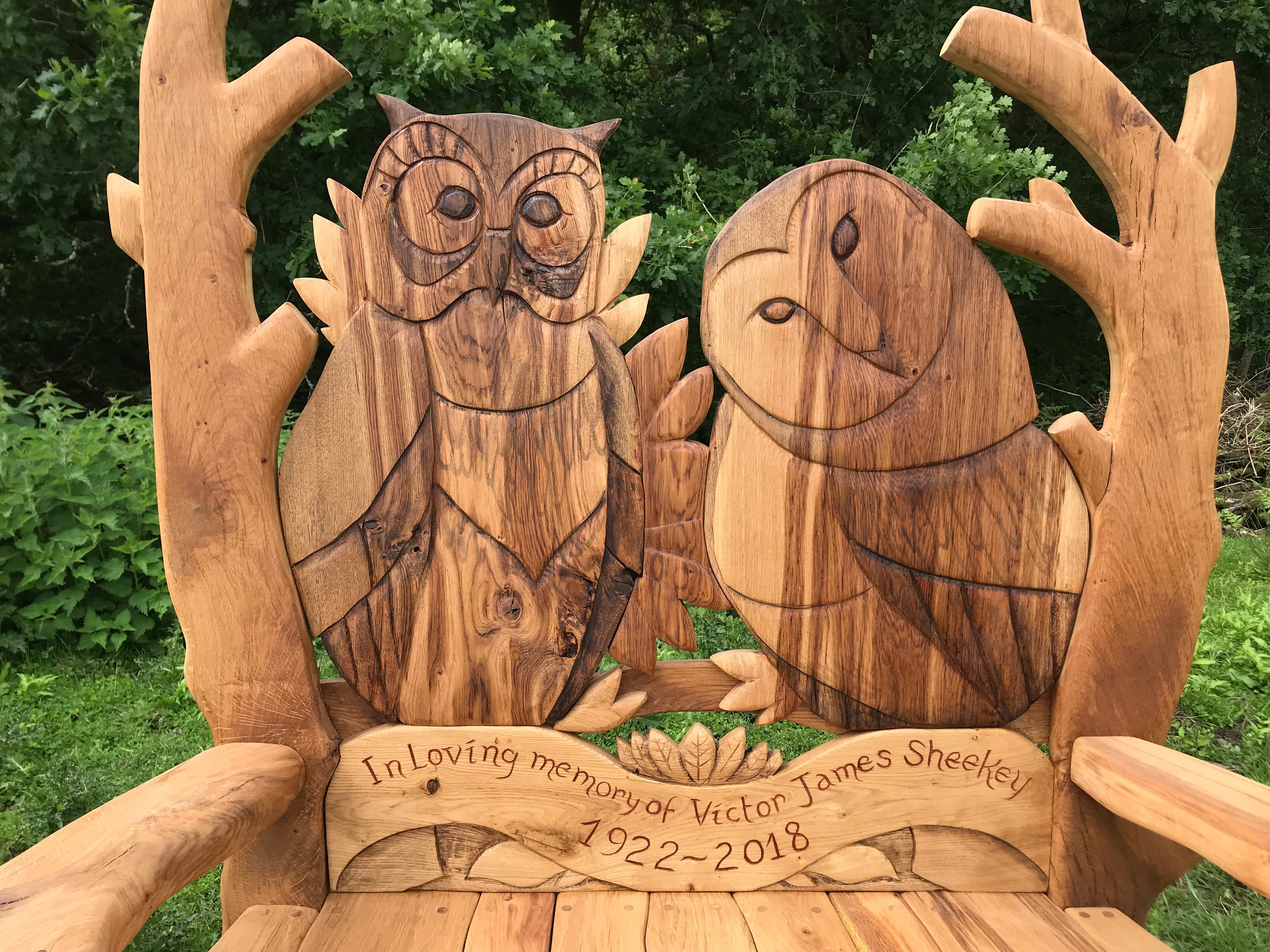 Memorial bench with owl carvings and dedication