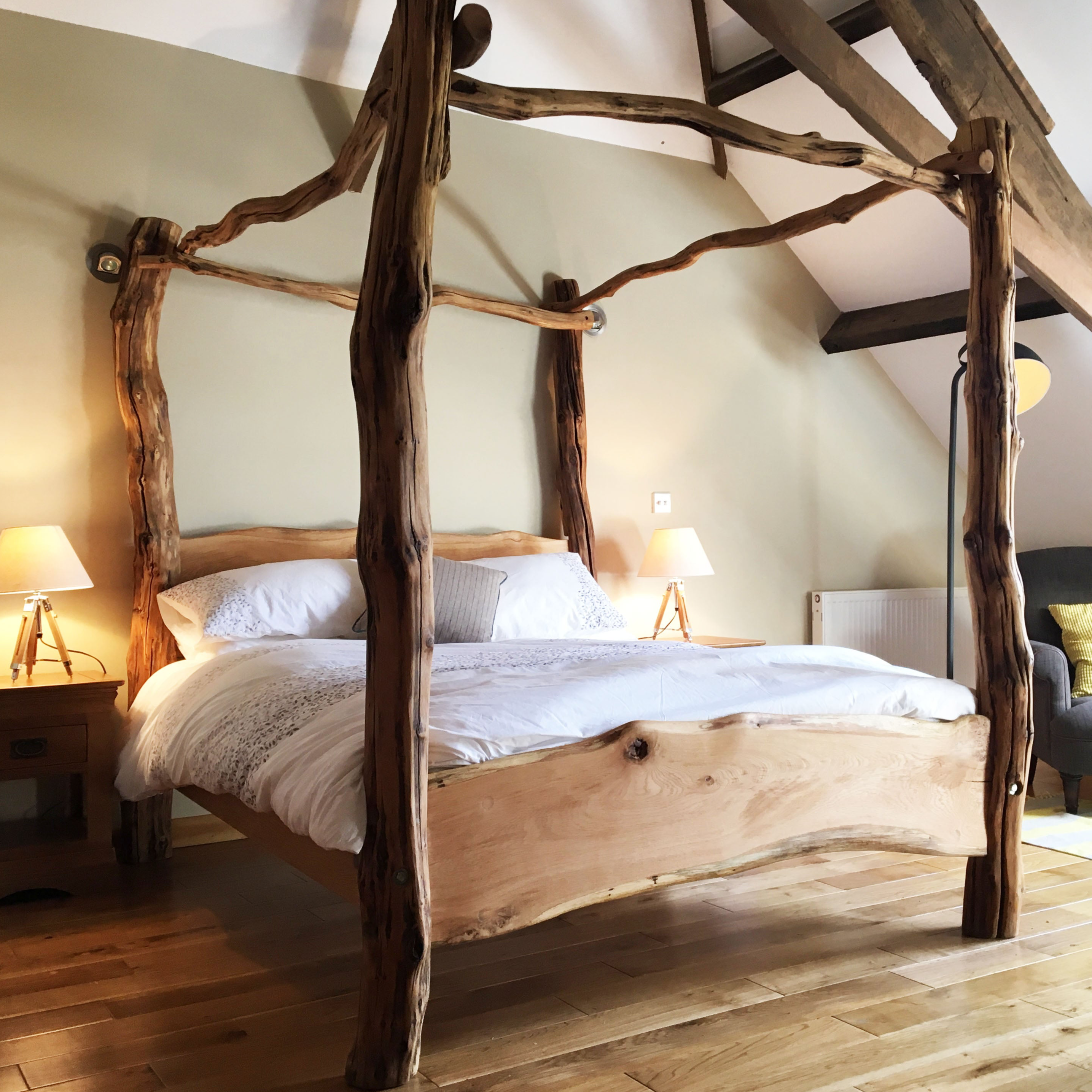 Handcrafted four-poster bed made from natural wood by Free Range Designs, featuring rustic wooden posts and a unique organic design that blends with modern bedroom decor.