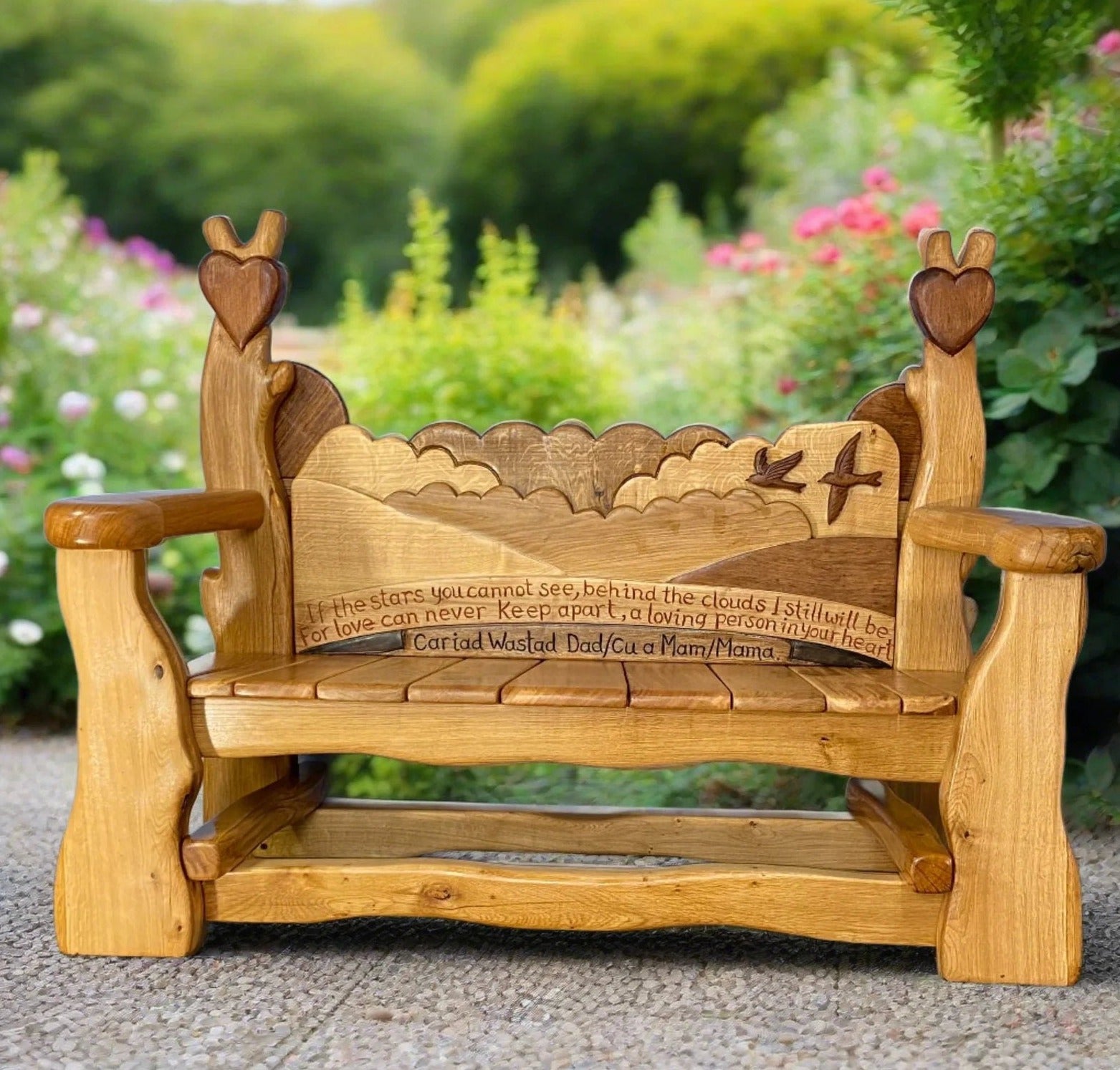 Memorial bench made from solid wood, featuring carved birds and a scenic backrest with an inscription dedicated to Isabel and Brian Stanley for their contributions to Randwick Primary School