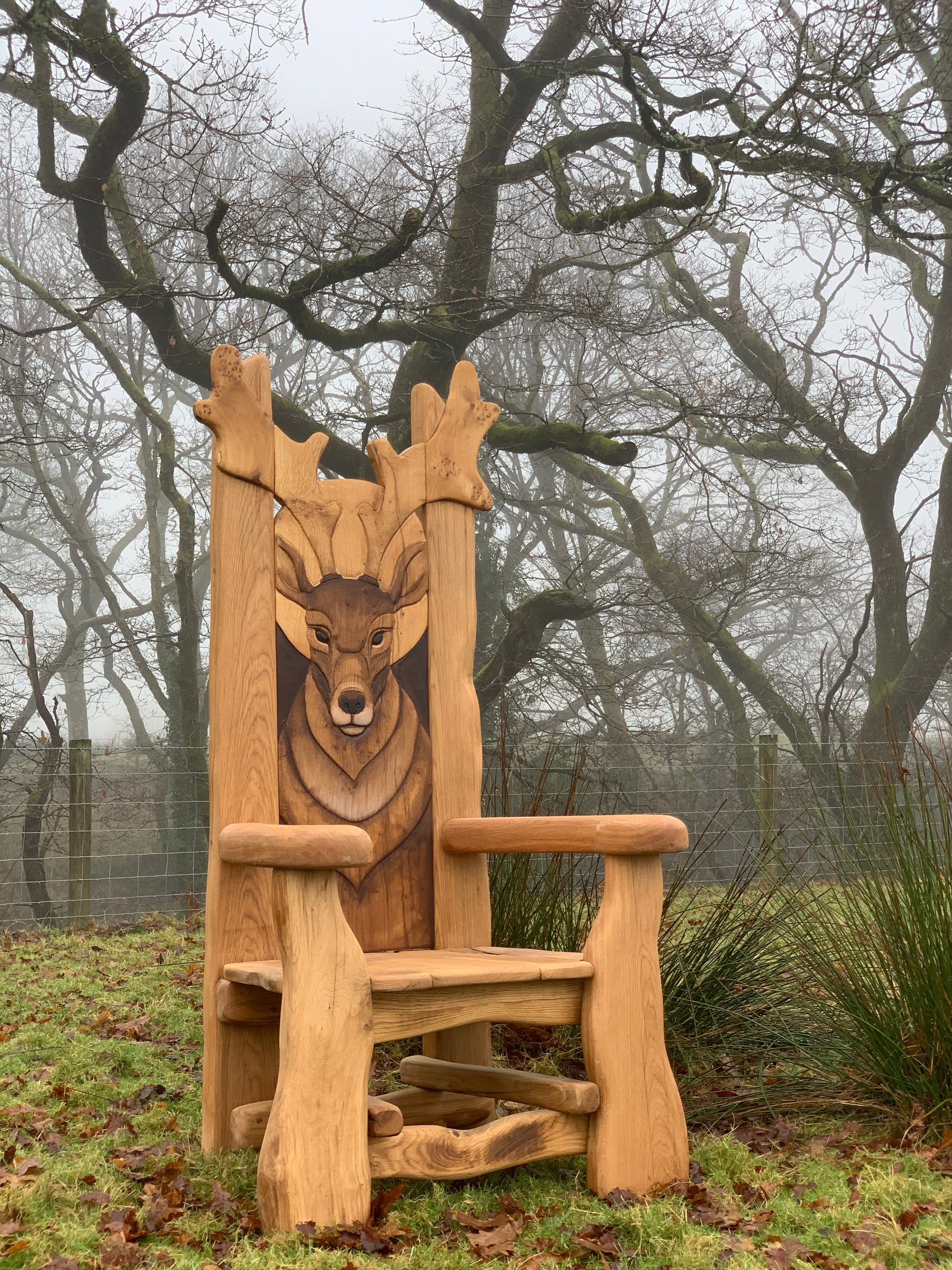 Wooden chair with deer carving in a foggy landscape.