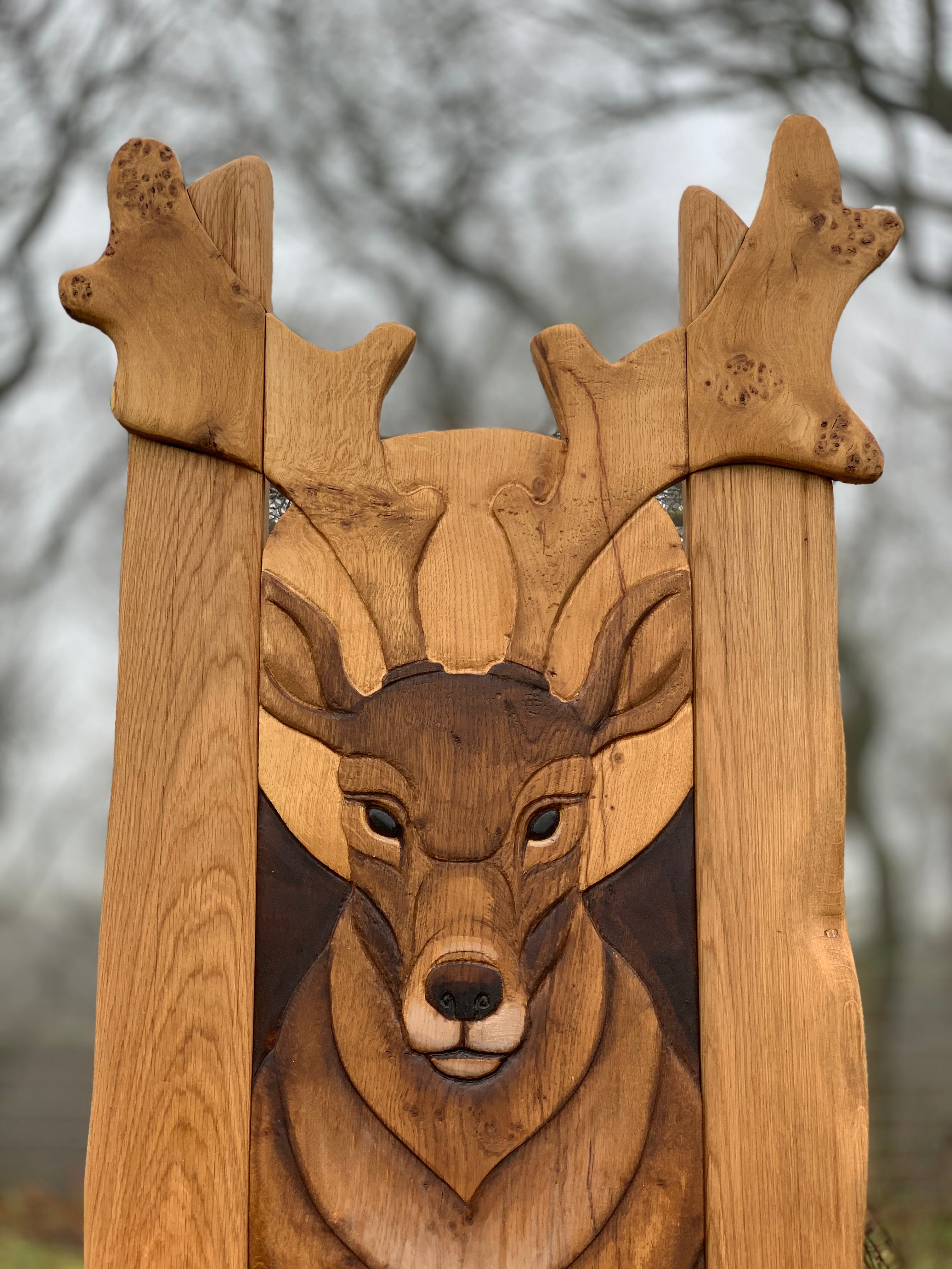 Close-up of deer carving on wooden chair in misty forest.