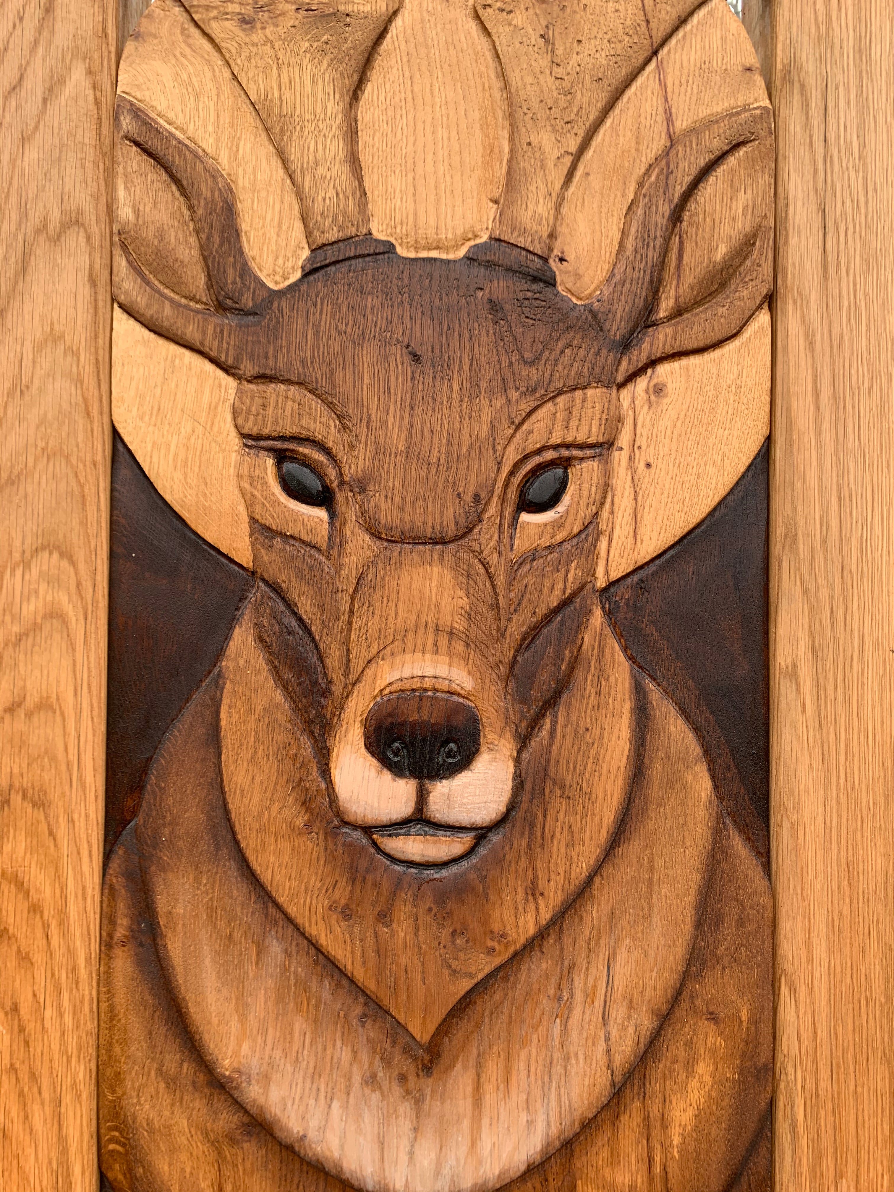 Close-up of deer carving on wooden chair.