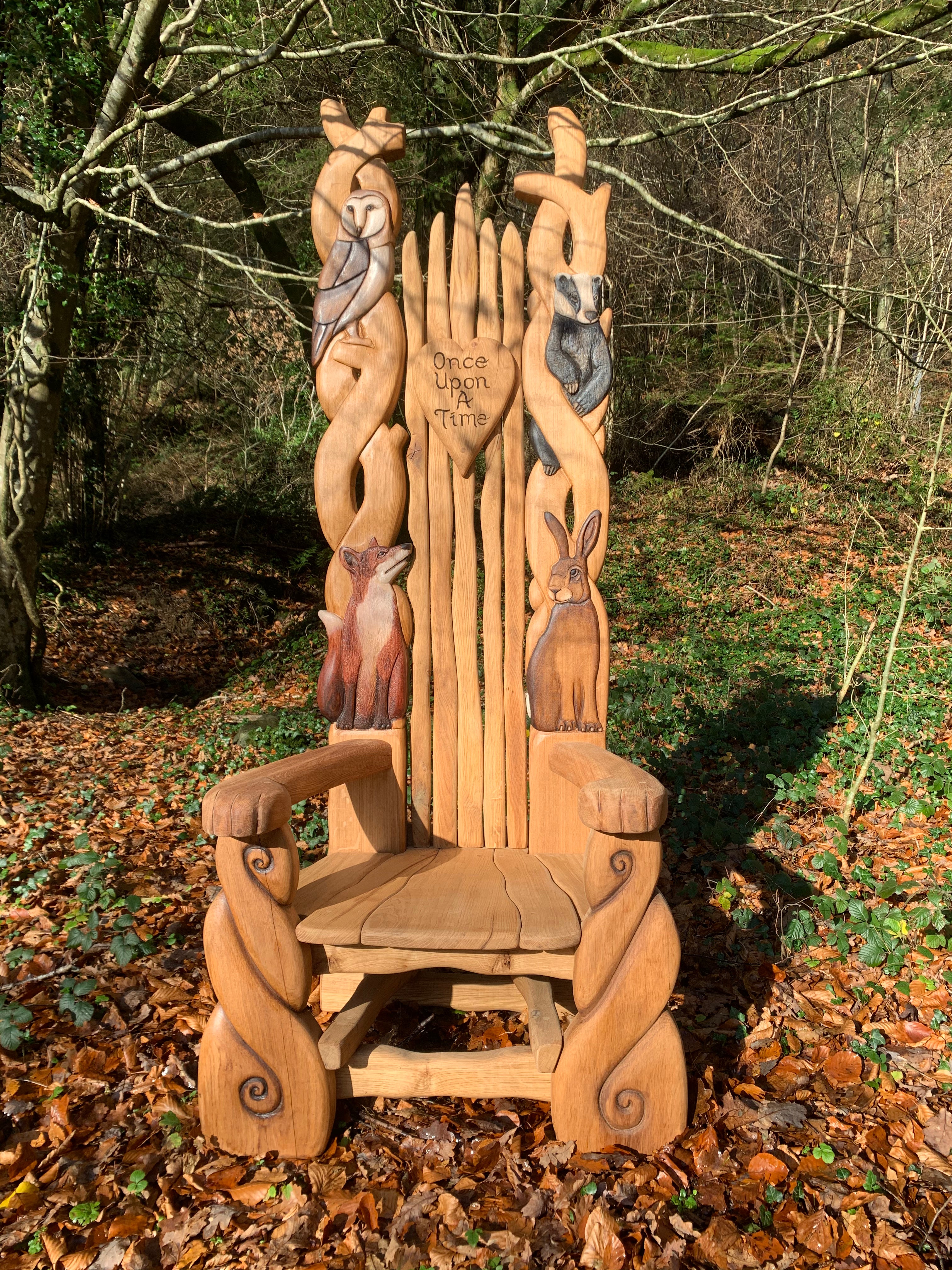 Wooden chair with animal carvings in a forest.