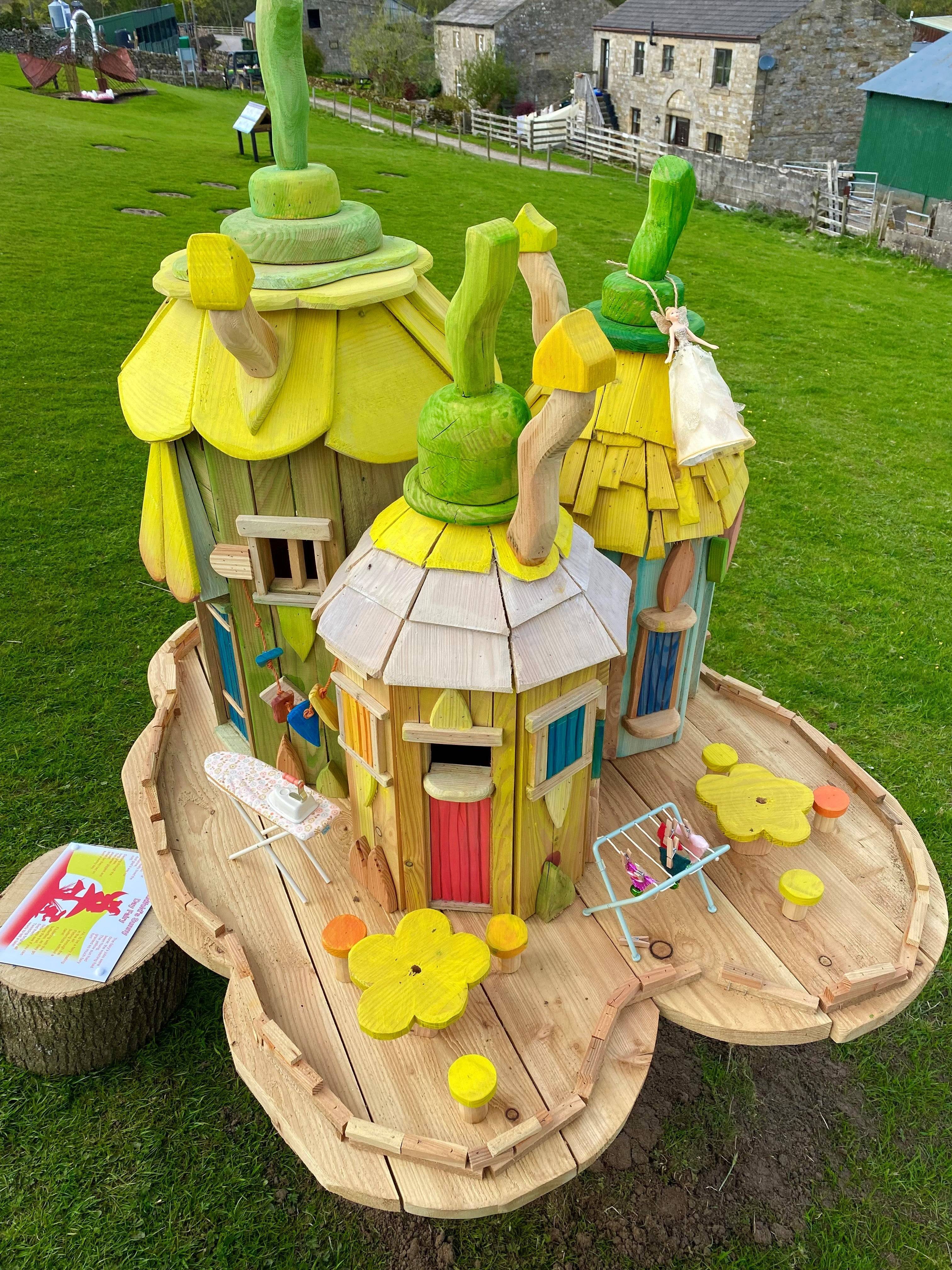 Cluster of fairy houses with yellow roofs on a wooden base