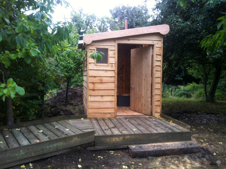 Compost toilet with wooden exterior and ramp in forest