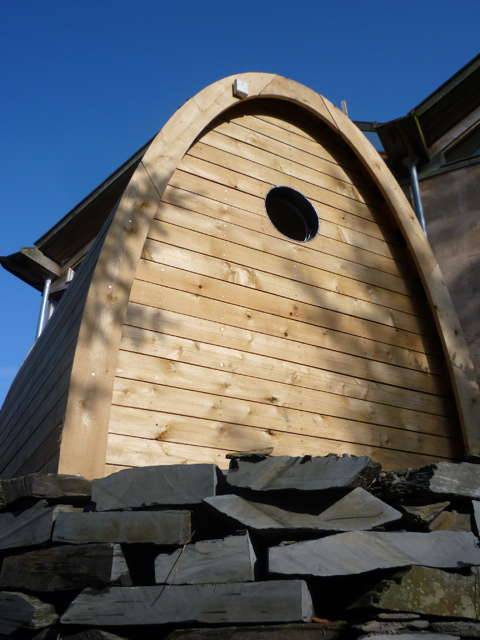 Front view of Timber Arc Composting Toilet with stone base