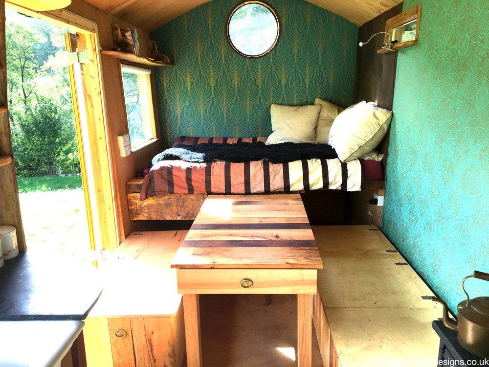 Shepherd's hut interior with bed and wooden furniture