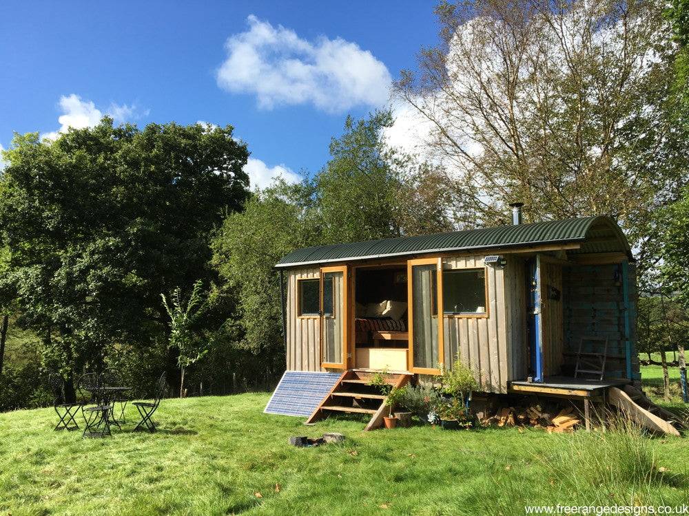 Shepherd's hut on grassy field with solar panel