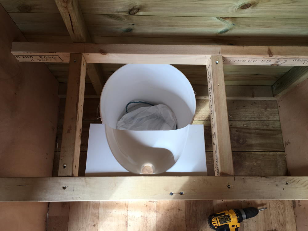 Urine separator installed in wooden compost toilet frame.