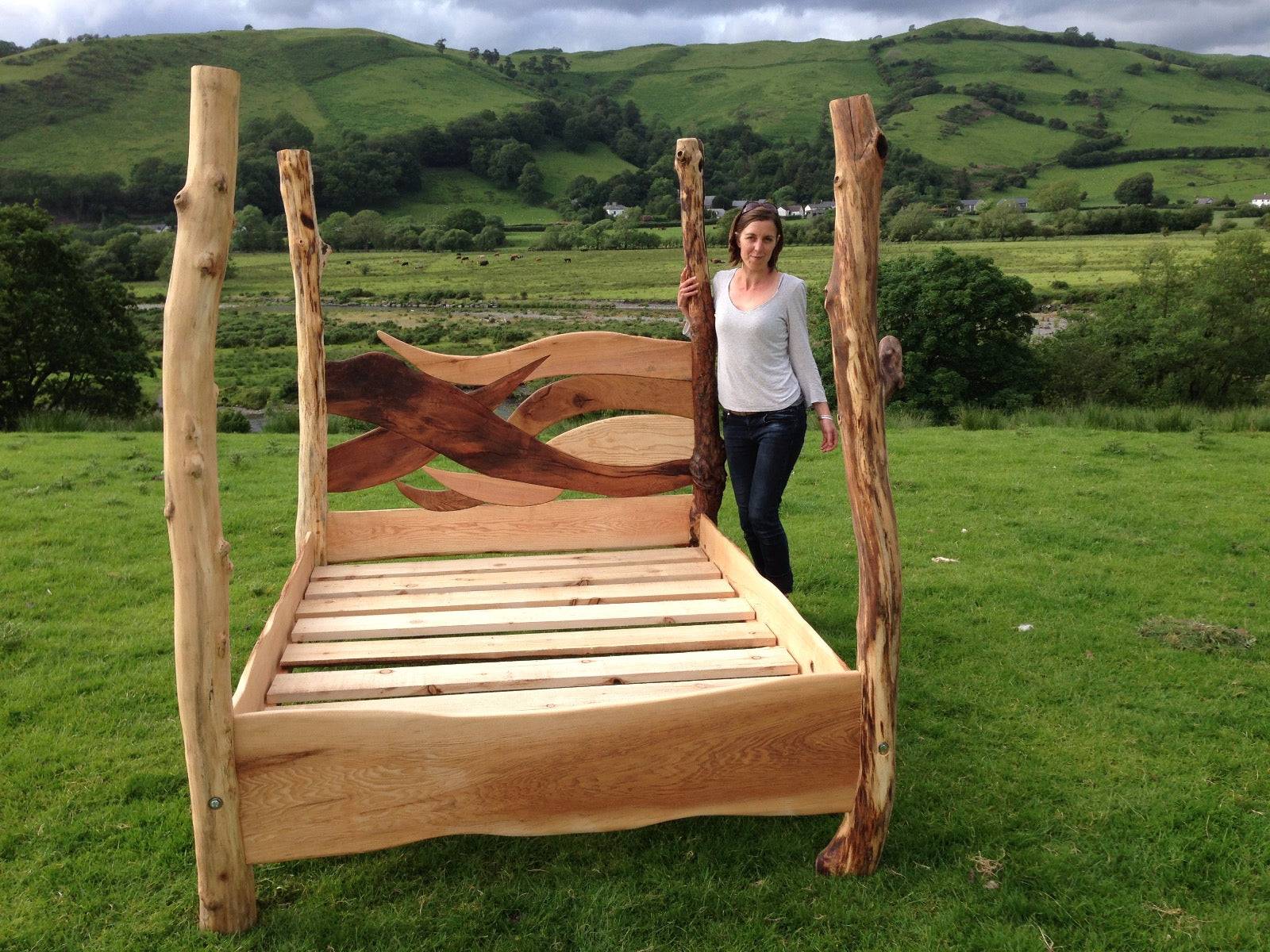 Woman standing beside rustic four-poster driftwood bed