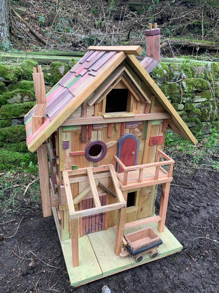 Wooden fairy house with a small cart