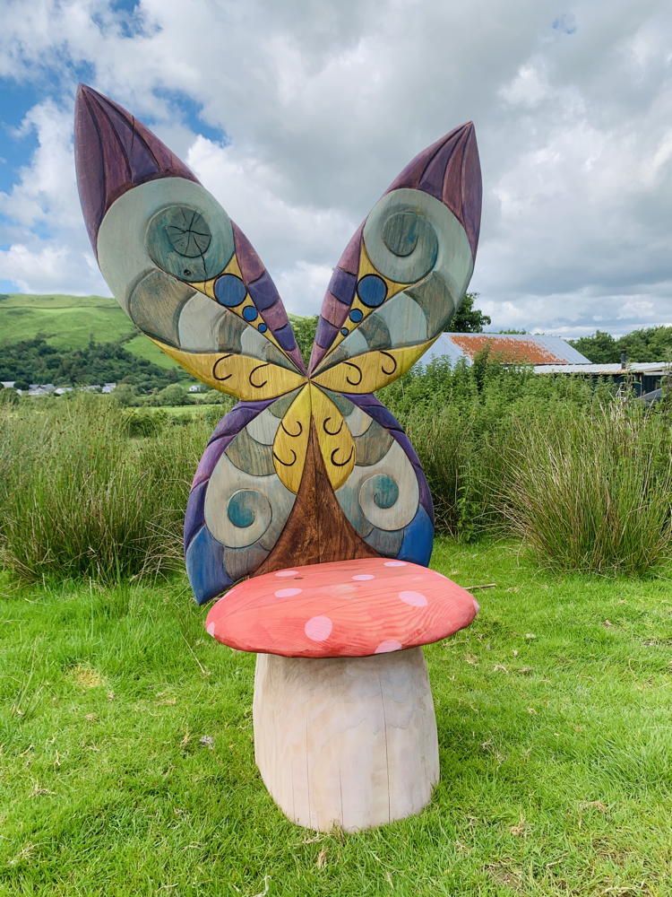 Whimsical fairy chair with butterfly wings in grassy area