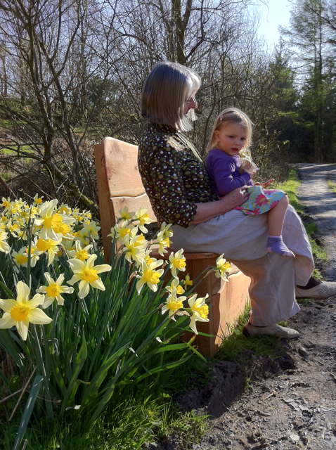 Side view of woman and child on wooden garden bench