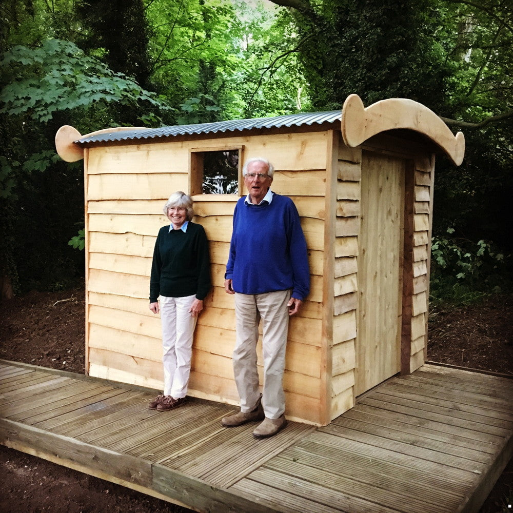 Elderly couple beside a wooden compost toilet