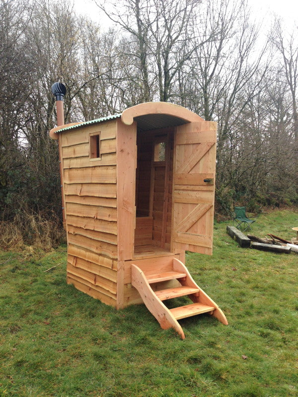 Wooden compost toilet with open door in field