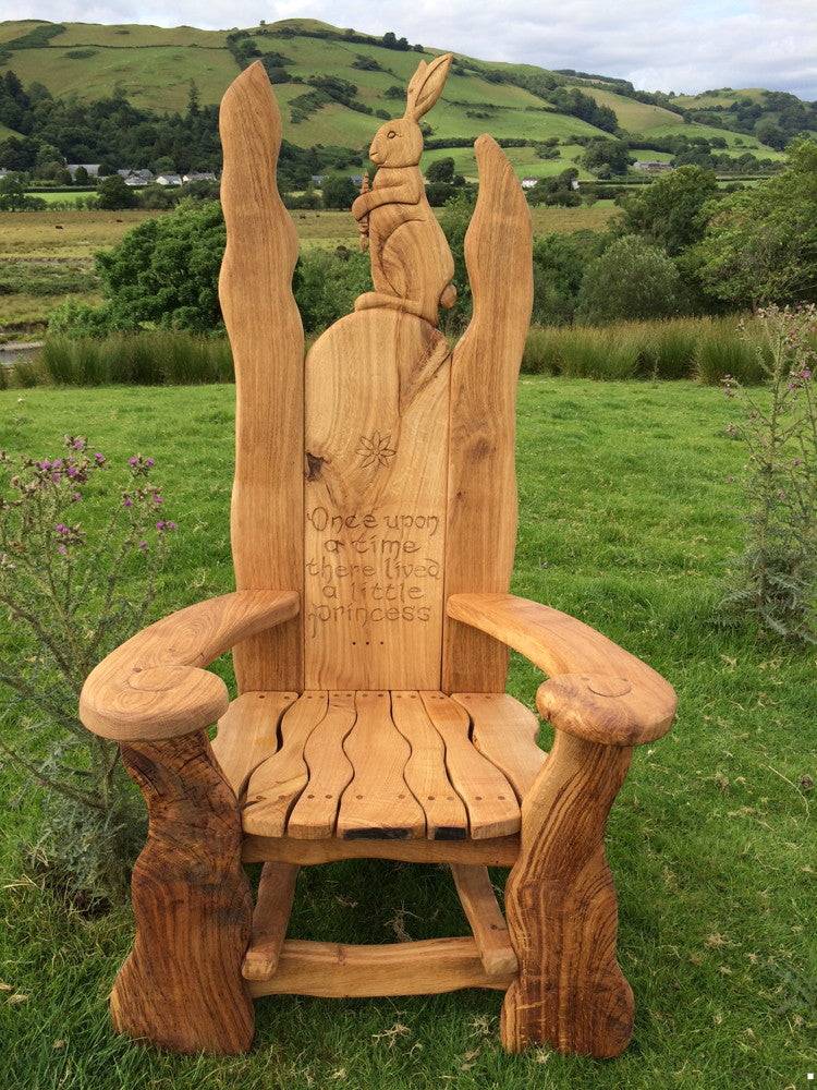 Oak storytelling chair with rabbit carving in scenic landscape