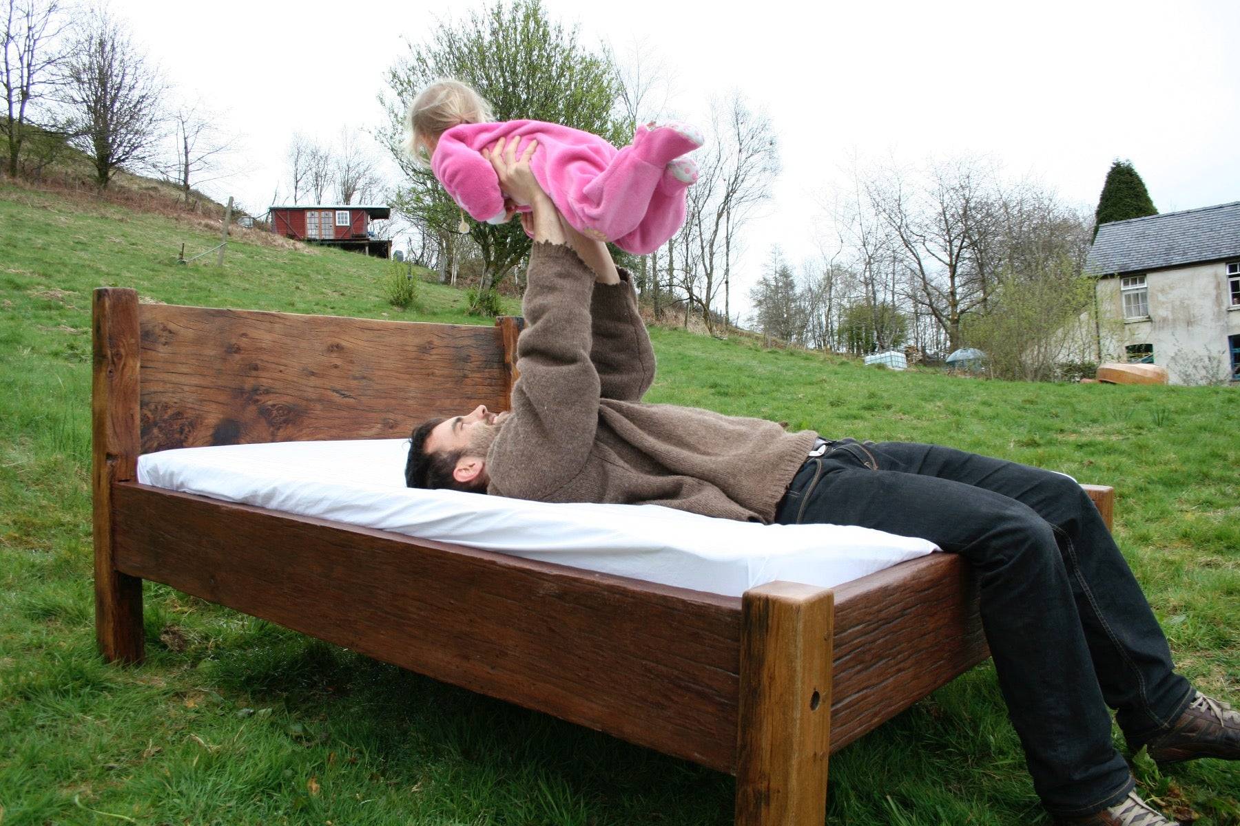 Man and child on reclaimed oak bed outdoors