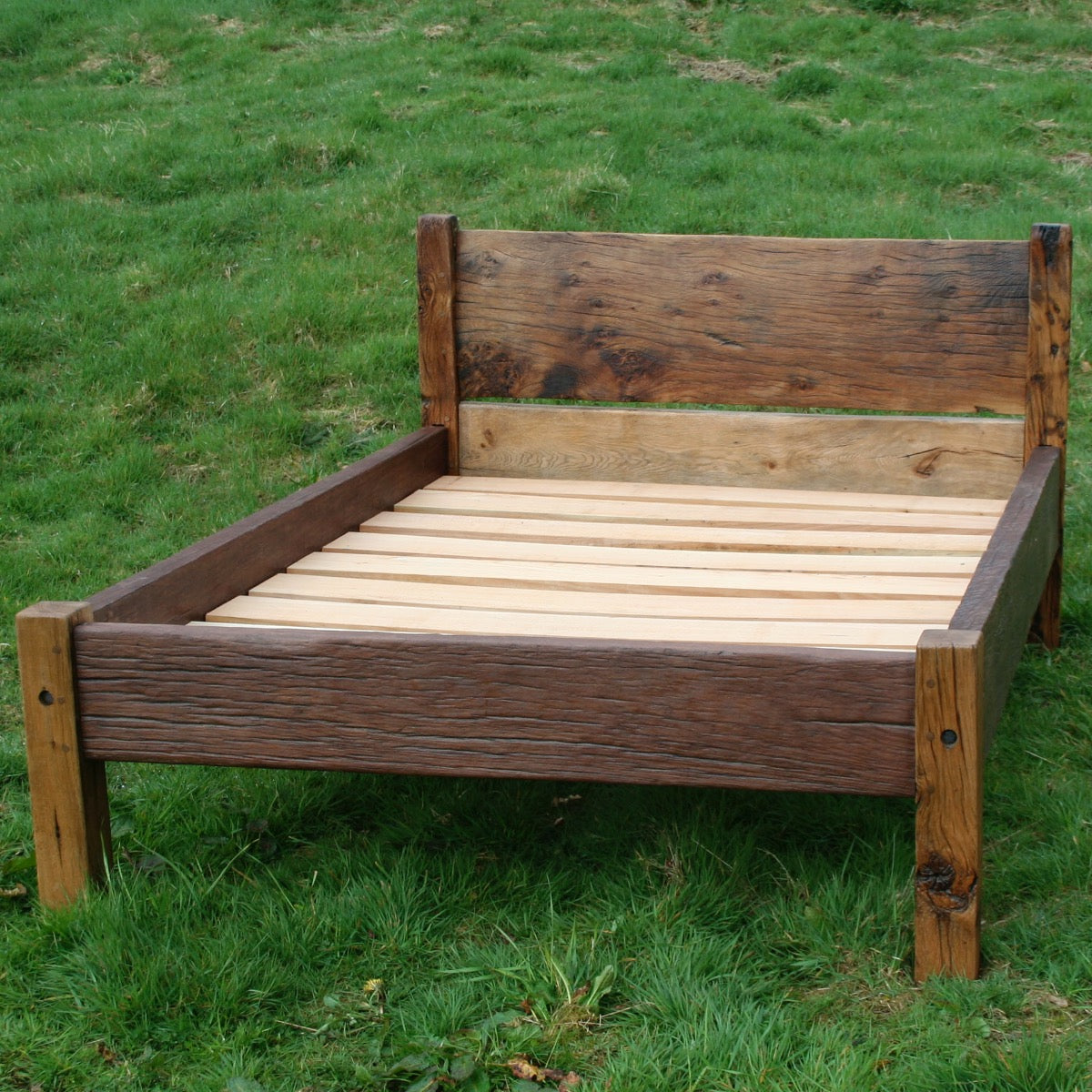 Handmade reclaimed oak bed on grass