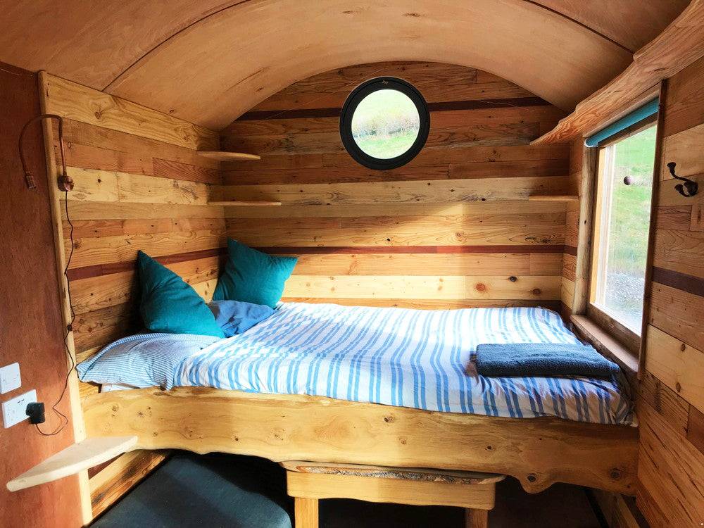 Comfortable bed inside the wooden Shepherd's Hut